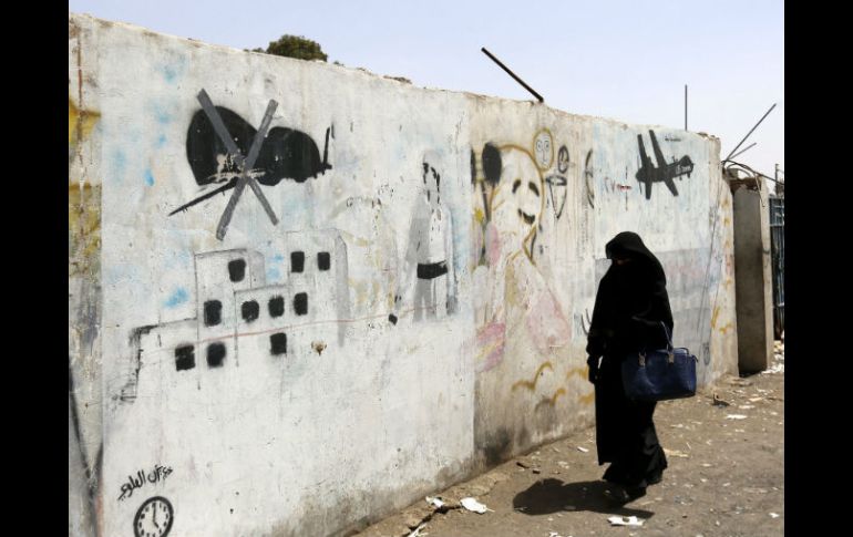 Una mujer camina junto a unas pinturas que se hicieron en protesta por los ataques con drones estadounidenses. EFE / Y. Arhab