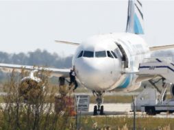 Un hombre sale de la ventana de la cabina del Airbus A-320, luego que la aeronave aterrizara en Chipre por una amenaza. AFP / B. Mehri