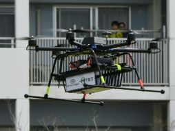 Vecinos observan con curiosidad a un dron transportando un paquete de víveres. AFP / T. Yamanaka