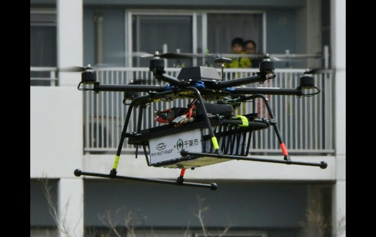 Vecinos observan con curiosidad a un dron transportando un paquete de víveres. AFP / T. Yamanaka