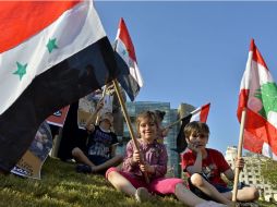 Niños sirios y libaneses ondean banderas durante una protesta en contra de la ruptura del alto el fuego en Siria. EFE / W. Hamzewh