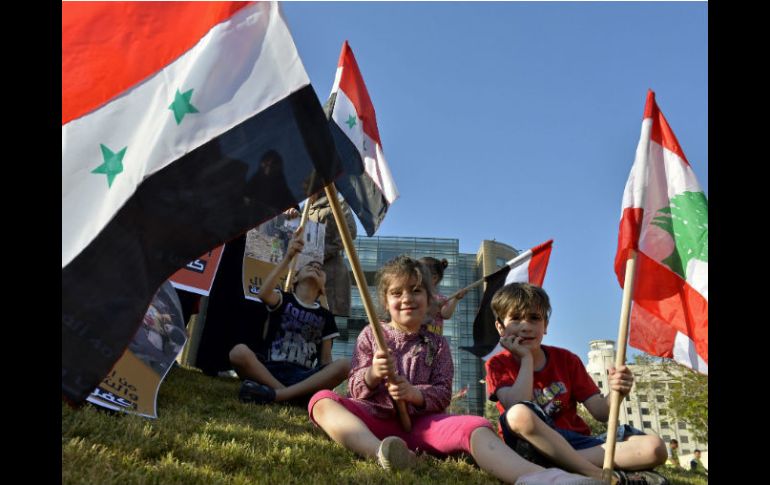 Niños sirios y libaneses ondean banderas durante una protesta en contra de la ruptura del alto el fuego en Siria. EFE / W. Hamzewh