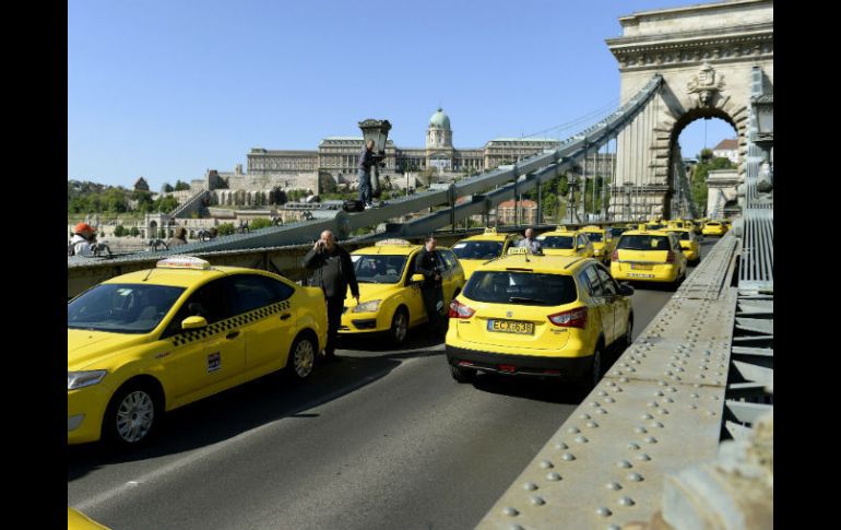 Taxistas forman una línea con sus vehículos en el Puente de las Cadenas durante la manifestación contra Uber. EFE / N. Bruzak