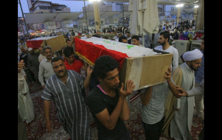 Participantes de un funeral multitudinario cargan ataúdes con los restos de sus seres queridos que ayer fallecieron en la explosión. AP / A. Khalil