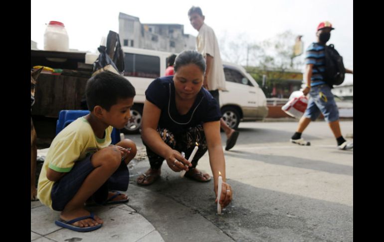 Personas colocan una vela en el lugar donde ocurrió el hecho. EFE / R. Malasig