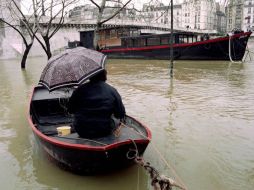 Una persona se traslada en bote para llegar a otro, cerca del puente de la Tournelle. EFE / E. Feferberg