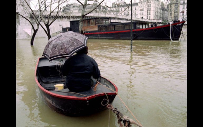 Una persona se traslada en bote para llegar a otro, cerca del puente de la Tournelle. EFE / E. Feferberg