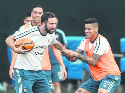 Gonzalo Higuaín, quien corre con un balón de rugby, es jaloneado por Marcos Rojo, en la práctica recreativa de la Albiceleste. EFE /