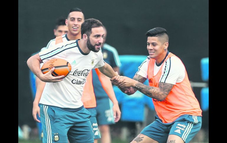 Gonzalo Higuaín, quien corre con un balón de rugby, es jaloneado por Marcos Rojo, en la práctica recreativa de la Albiceleste. EFE /