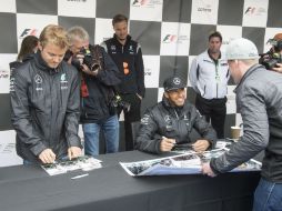 Nico Rosberg (izq.) y Lewis Hamilton firman autógrafos previo a la competencia. AP / R. Remiorz