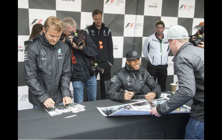 Nico Rosberg (izq.) y Lewis Hamilton firman autógrafos previo a la competencia. AP / R. Remiorz