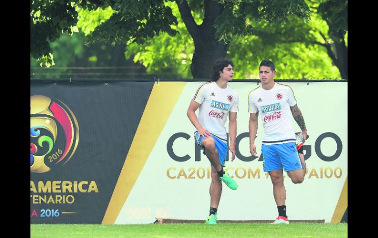 Stefan Moreno (izquierda) hace estiramientos junto a James Rodríguez durante la sesión de entrenamiento de ayer. AFP /