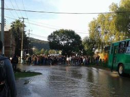 Algunos estudiantes tuvieron que cruzar las calles para arribar al edificio completamente mojados. ESPECIAL /