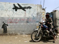 Un motorista pasa delante de un grafiti hecho en protesta contra las operaciones estadounidenses en Yemen. EFE / Y. Arhab