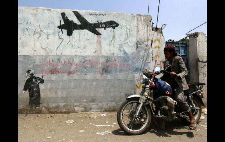 Un motorista pasa delante de un grafiti hecho en protesta contra las operaciones estadounidenses en Yemen. EFE / Y. Arhab