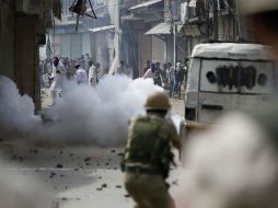 Varios jóvenes se protegen contra el gas lacrimógeno lanzado por la policía india durante unas revueltas en Srinagar. EFE / F. Khan