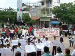 Los niños portan pancartas en las que se lee: 'Viva mi patria' y 'Moderar la opulencia y la indigencia. Nos faltan 43'. TWITTER / @AlbaniaOC