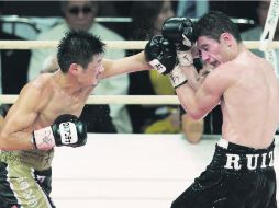 Hozumi Hasegawa golpea con la izquierda a Hugo 'Cuatito' Ruiz (derecha) durante la pelea por el título del CMB peso supergallo. AFP /