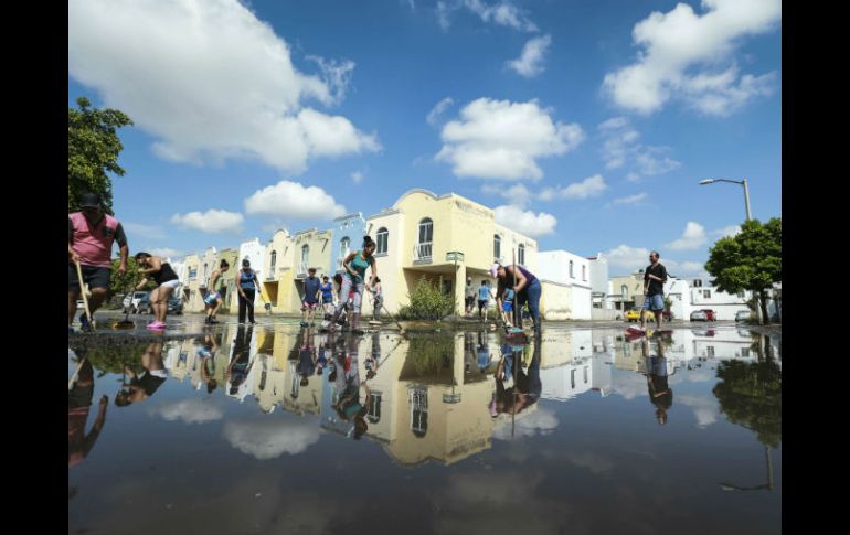 Vecinos del coto Jardines del Edén, en Tlajomulco, tratan de retirar el agua que quedó estancada en sus calles. EL INFORMADOR / A. García