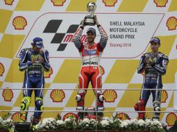 Andrea Dovizioso levanta su trofeo mientras es observado por Valentino Rossi y Jorge Lorenzo. EFE / F. Ismail