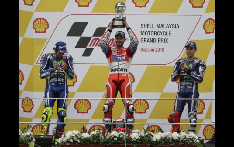 Andrea Dovizioso levanta su trofeo mientras es observado por Valentino Rossi y Jorge Lorenzo. EFE / F. Ismail