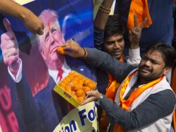 Un miembro de Hindu Sena 'alimenta' un retrato de Trump con dulces. AP / M. Swarup