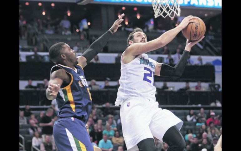 Enrachados. Marco Belinelli (#21), de Charlotte, se eleva para encestar ante la marca de Joe Johnson, de Utah. AP / C. Burton