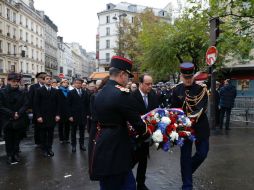 Hollande coloca un arreglo floral en el área de cafés y restaurantes donde ocurrió uno de los atentados. AP / P. Wojazer