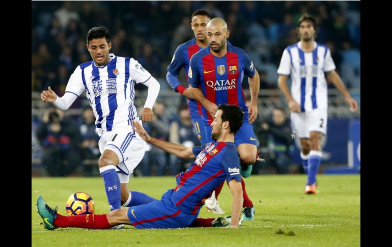 Busquets, del Barcelona, se barre para detener al mexicano. EFE / J. Herrero