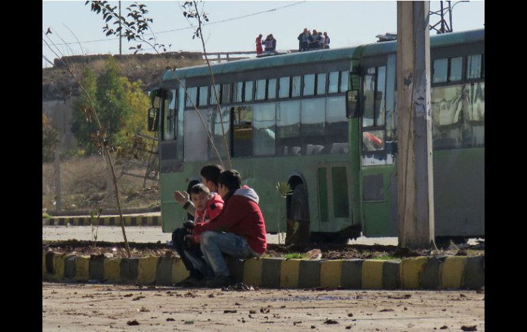 Niños sirios esperan afuera de un autobús a ser evacuados con sus familias. AFP / STRINGER