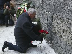 Un sobreviviente coloca una ofrenda en el muro de ejecución del antiguo campo de exterminio nazi. AP / C. Sokolowski