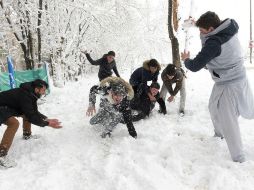 Varios niños se divierten en una guerra de bolas de nieve. AFP / S. Marai