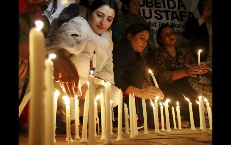 Varias personas colocan velas encendidas en honor a las víctimas mortales. EFE / S. Akber