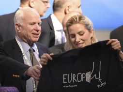 McCain sonríe al recibir una camiseta de la periodista y política Svitlana Zalishchuk, en la Conferencia sobre Seguridad. AP /