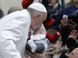 El Papa Francisco besa a un bebé antes de comenzar su tradicional audiencia general de los miércoles. AP / A. Medichini