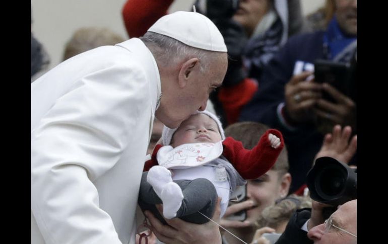 El Papa Francisco besa a un bebé antes de comenzar su tradicional audiencia general de los miércoles. AP / A. Medichini