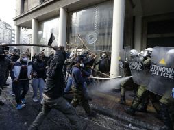 Los agricultores prendieron fuego a contenedores de basura y lanzaron piedras contra el edificio y contra las fuerzas antidisturbios. AP / T. Stavrakis