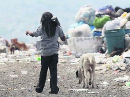 Una menor con su perro caminan rumbo a su casa entre montañas de basura en el vertedero municipal del Bordo de Xochiaca. EFE /