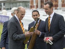 El duque de Edimburgo admira un valioso bate de críquet en la reapertura del Lord's Cricket Ground, ayer en Londres. AFP / A. Edwards