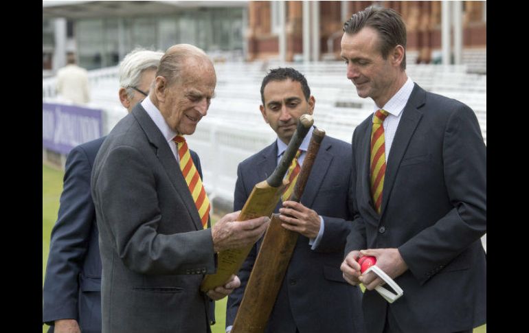 El duque de Edimburgo admira un valioso bate de críquet en la reapertura del Lord's Cricket Ground, ayer en Londres. AFP / A. Edwards