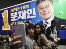 Junto a una imagen de Moon Jae-in, una pareja se tomó una foto en medio de la algarabía por la elección del nuevo mandatario. AP / Y. Ahn