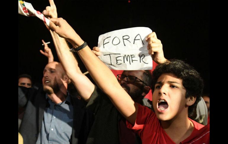 Manifestantes a las afueras del Palacio del Planalto con un cartelón que reza 'Fuera Temer'. AFP / E. Sa