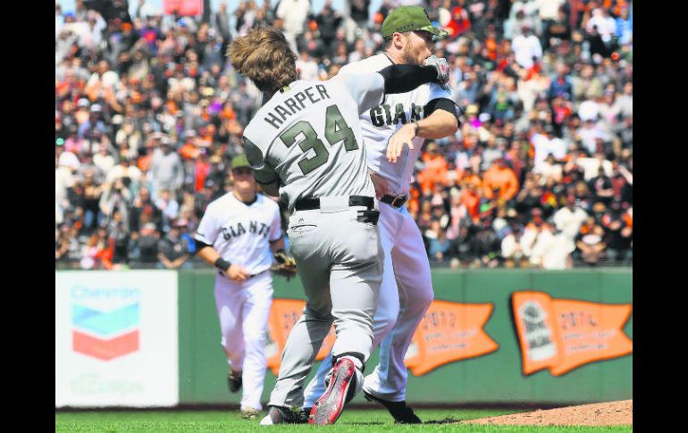 Bryce Harper (#34) lanza un puñetazo al rostro de Hunter Strickland, quien lo golpeó de manera intencional con la bola el lunes pasado. AFP /