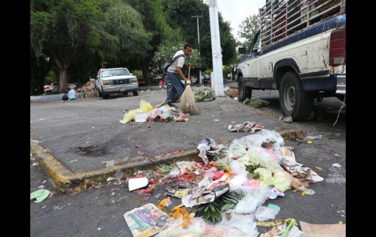 Un hombre barre la basura que dejó el tianguis de la colonia Constitución. EL INFORMADOR / G. Gallo