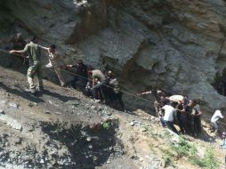 Policías y vecinos de los alrededores apoyan en las labores de rescate de heridos y extracción de cadáveres apoyados con cuerdas. AFP /