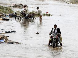 Varios motoristas conducen por una carretera inundada y llena de basura tras una fuerte lluvia en Saná. EFE / Y. Arhab