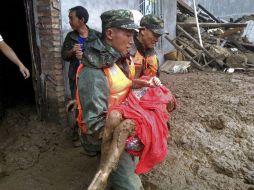 Rescatistas llevan a una persona que lograron sacar de entre toneladas de lodo y tierra, a causa de las lluvias. EFE /  S. Mingshi