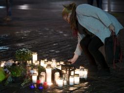 Una mujer deposita una flor en un monumento impsovisado para homenajear a las víctimas del ataque. AP / V. Moilanen