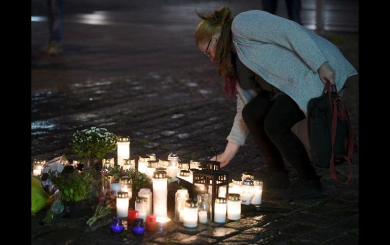 Una mujer deposita una flor en un monumento impsovisado para homenajear a las víctimas del ataque. AP / V. Moilanen