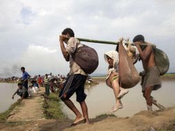 Dos hombres musulmanes de la minoría rohinyá llevan a una mujer mayor en Telnaf, al entrar en Bangladesh. EFE / STR